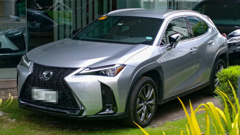 Lexus UX 300h F SPORT en color Iridio Sonic, visto de tres cuartos delantero frente a un concesionario