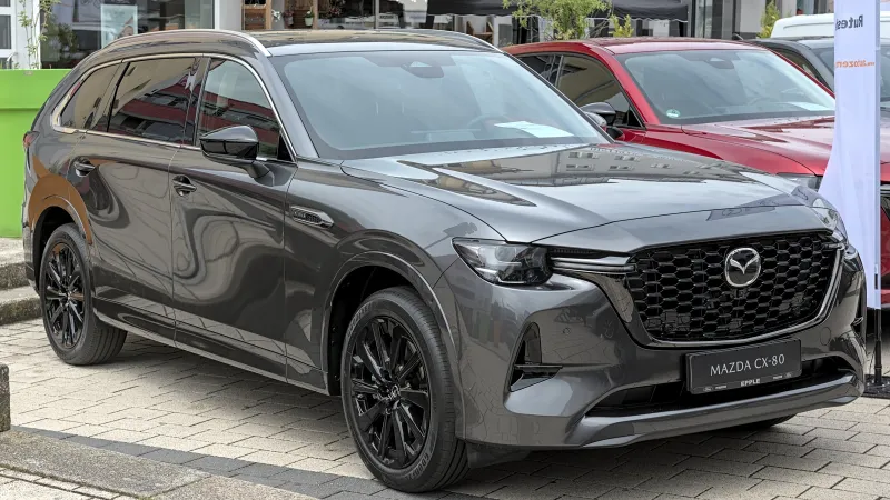 Mazda CX-80 diésel microhíbrido gris oscuro con llantas negras, aparcado y visto de tres cuartos delantero