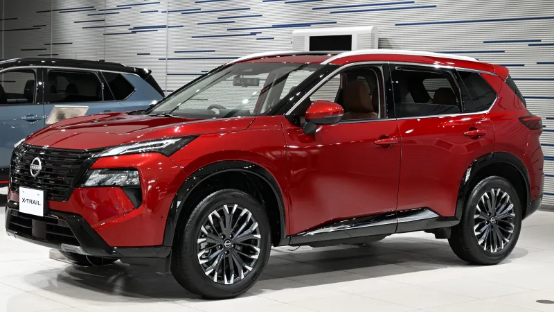 Nissan X-Trail e-4ORCE de la generación actual, rojo, en una sala de exposición, visto de tres cuartos delantero
