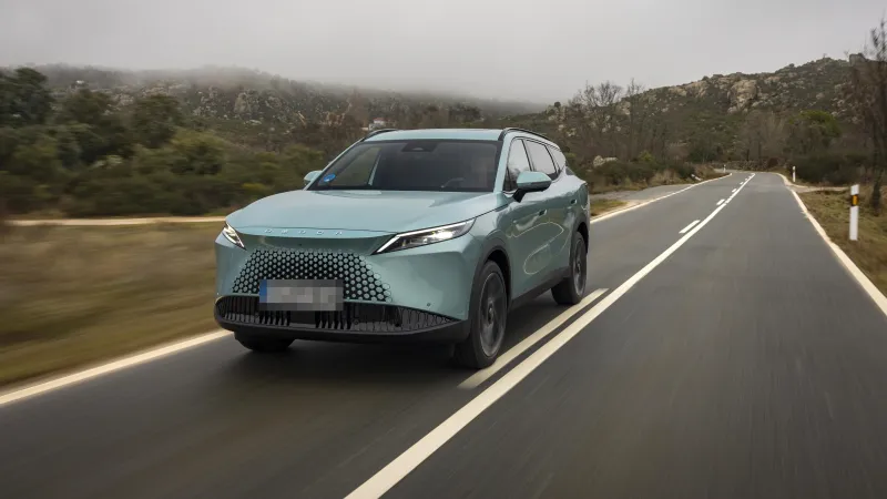Omoda 7 SHS híbrido enchufable verde claro circulando por una carretera de montaña, visto de tres cuartos delantero