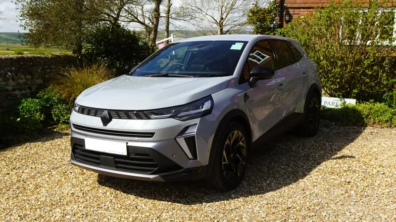 Renault Symbioz E-Tech full hybrid gris plata aparcado sobre grava, visto de tres cuartos delantero